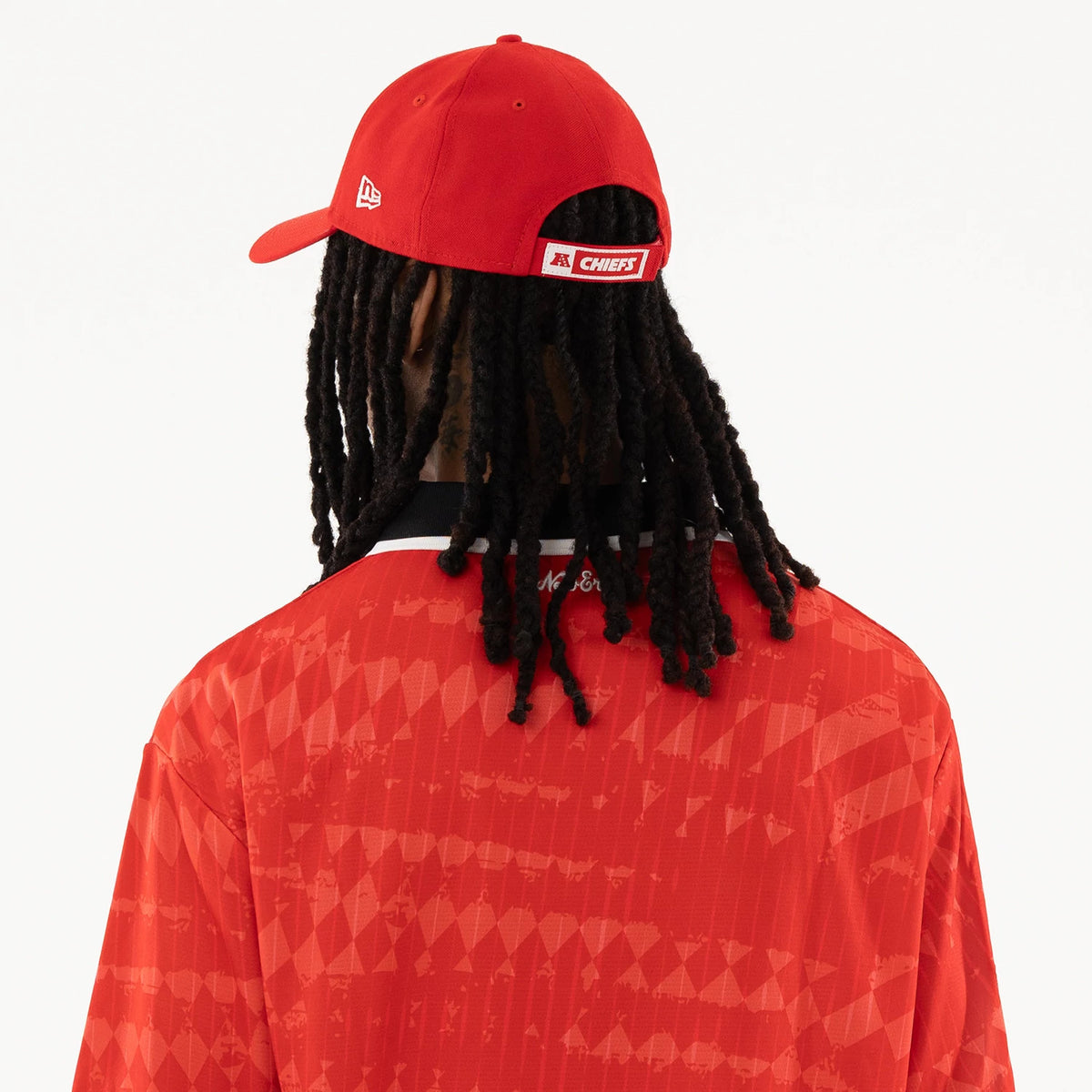 Kansas City Chiefs NFL Red Soccer Jersey, back view on a model wearing the matching cap, showing a red structured crown and white New Era flag logo embroidered on the left side above the cap's adjustable strap.