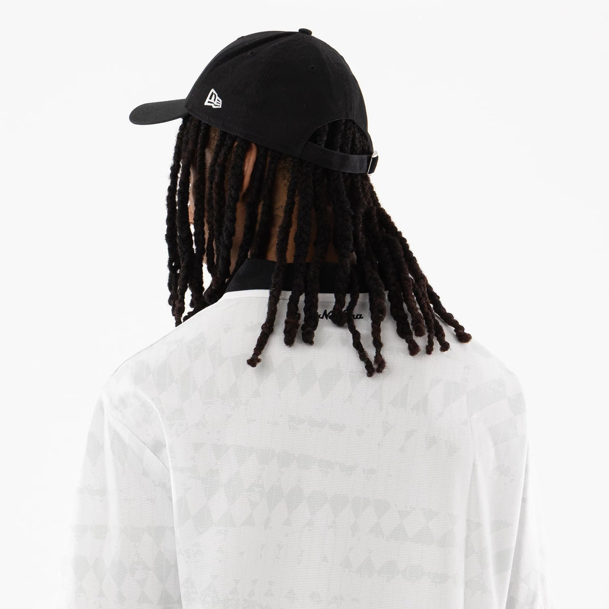 New Era White Soccer Jersey, rear view on a model wearing a black cap with the New Era flag logo on the left side, showing diamond pattern detailing on the white fabric and a black collar.