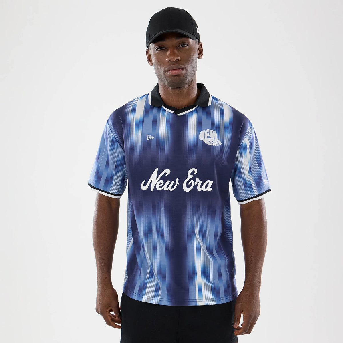 New Era Navy Soccer Jersey, front view on a model wearing a black cap, featuring a blue and white digital pattern, the New Era text logo across the chest, and a white collar with black trim.
