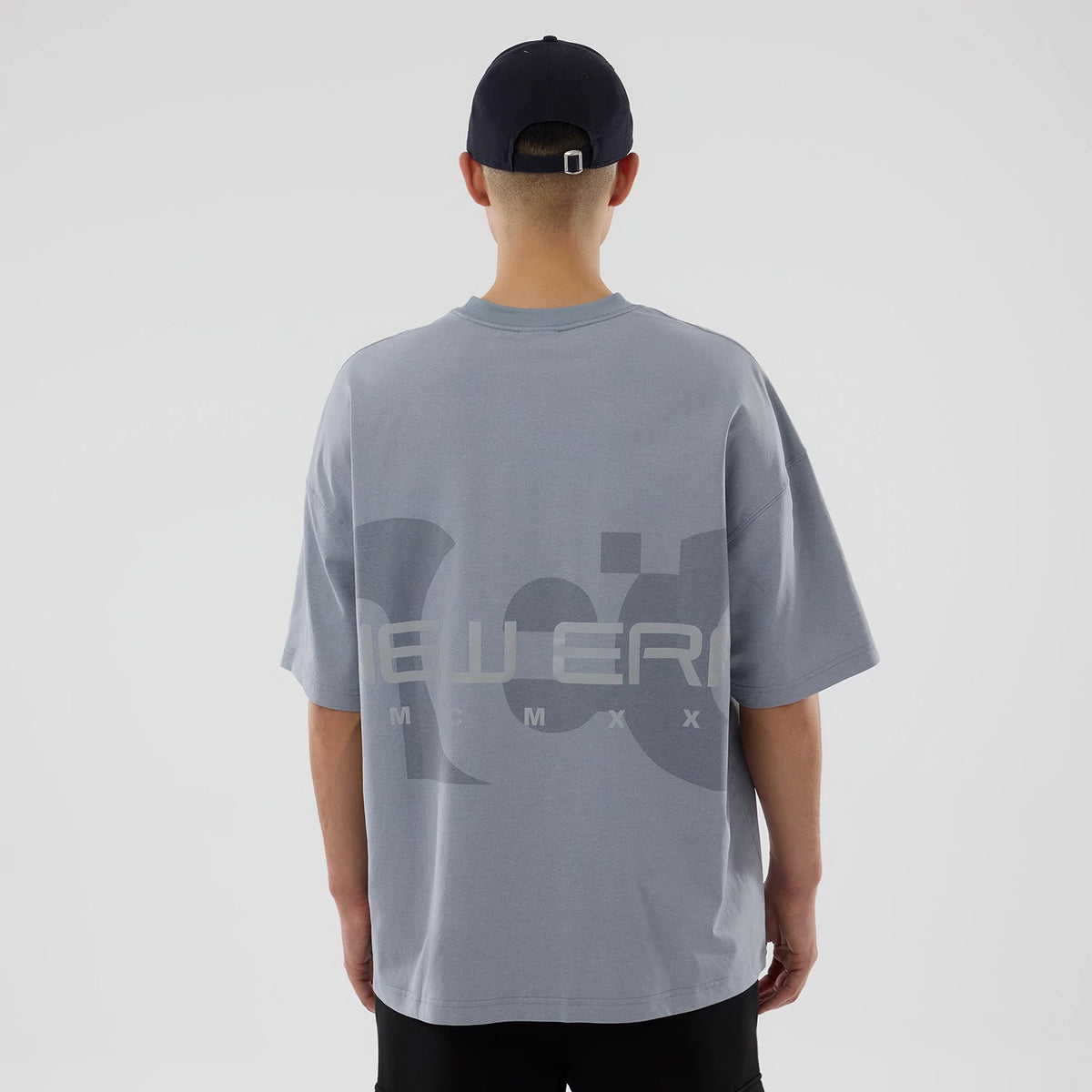 The model is wearing this New Era NEC Logo Oversized T-Shirt in grey. 2