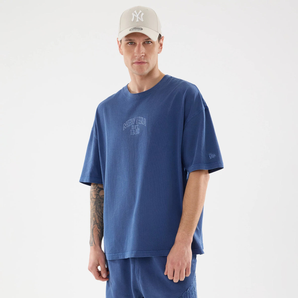 New Era Graphic Street Archived Blue Oversized T-Shirt, on-model view featuring a blue oversized t-shirt with a raised New Era logo on the chest and a small raised logo on the left sleeve.