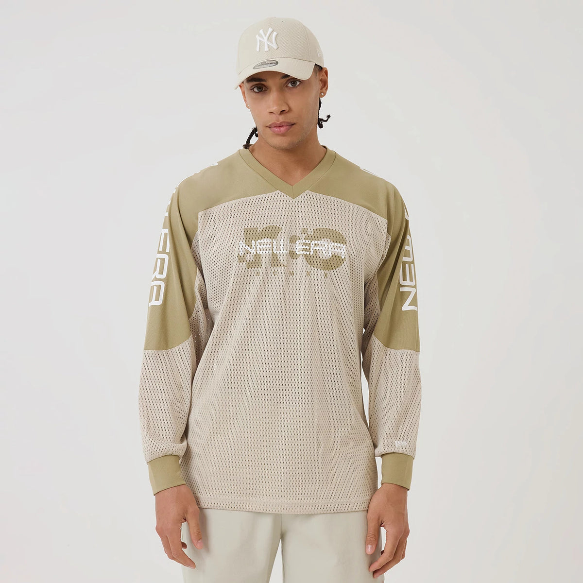New Era NEC Logo Beige Long Sleeve Jersey, front view on a model wearing a matching beige cap, featuring a white mesh design with NEC lettering centrally printed and white New Era branding down both sleeves.