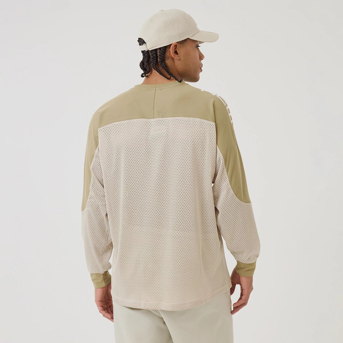 New Era NEC Logo Beige Long Sleeve Jersey, back view on a model wearing a beige cap, featuring mesh fabric on the lower back and sleeves, and contrasting solid beige panels across the shoulders and elbows.