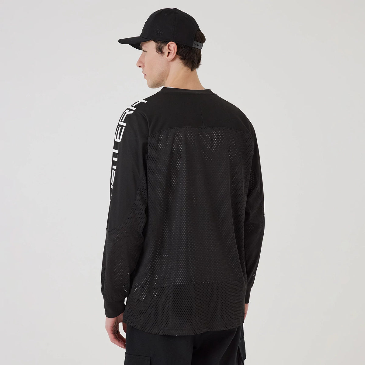New Era NEC Logo Black Long Sleeve Jersey, back view on a model also wearing a black cap, featuring large white NEC lettering down the right sleeve and mesh detailing across the back.
