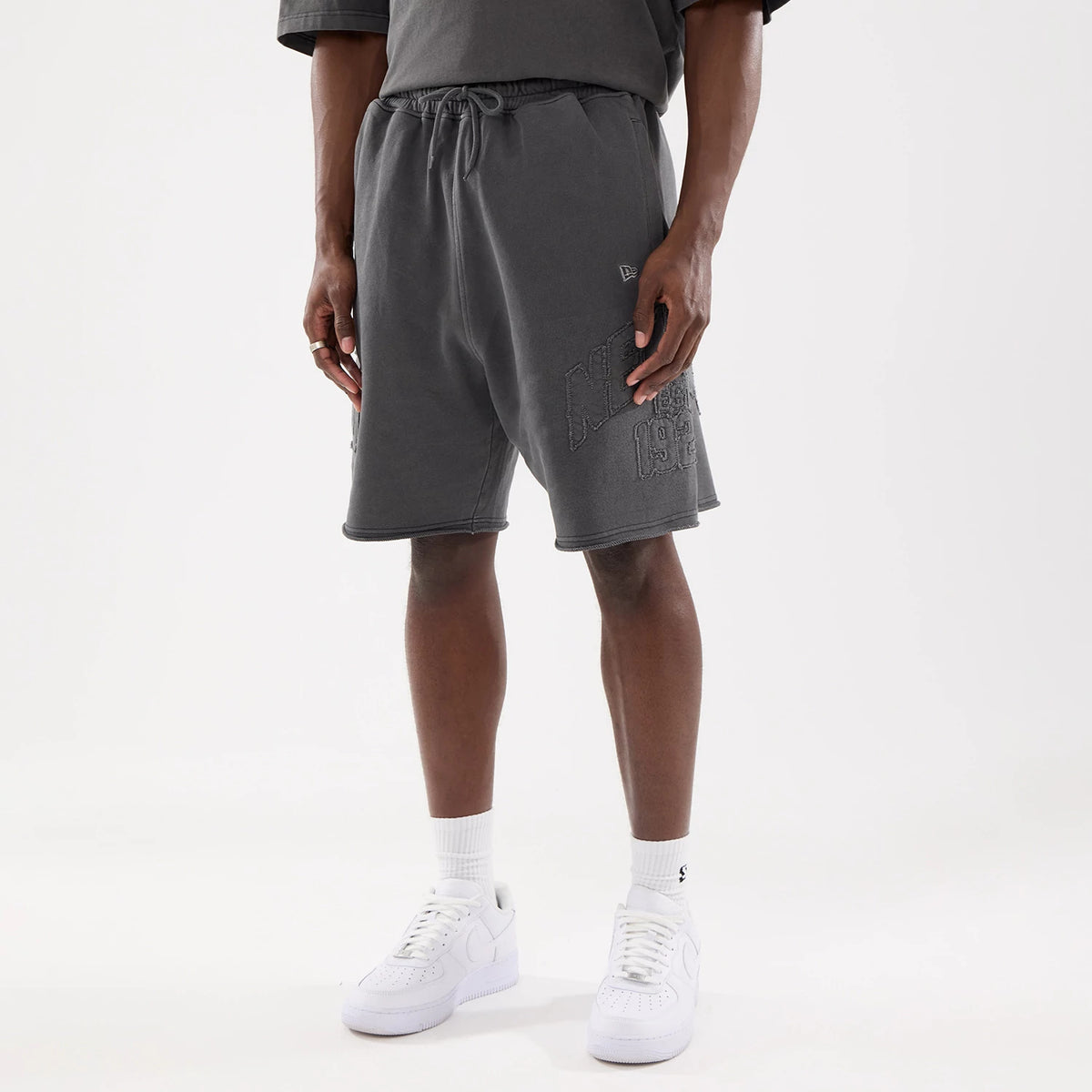 The model is wearing this New Era Street Archived Oversized Shorts in black. 1