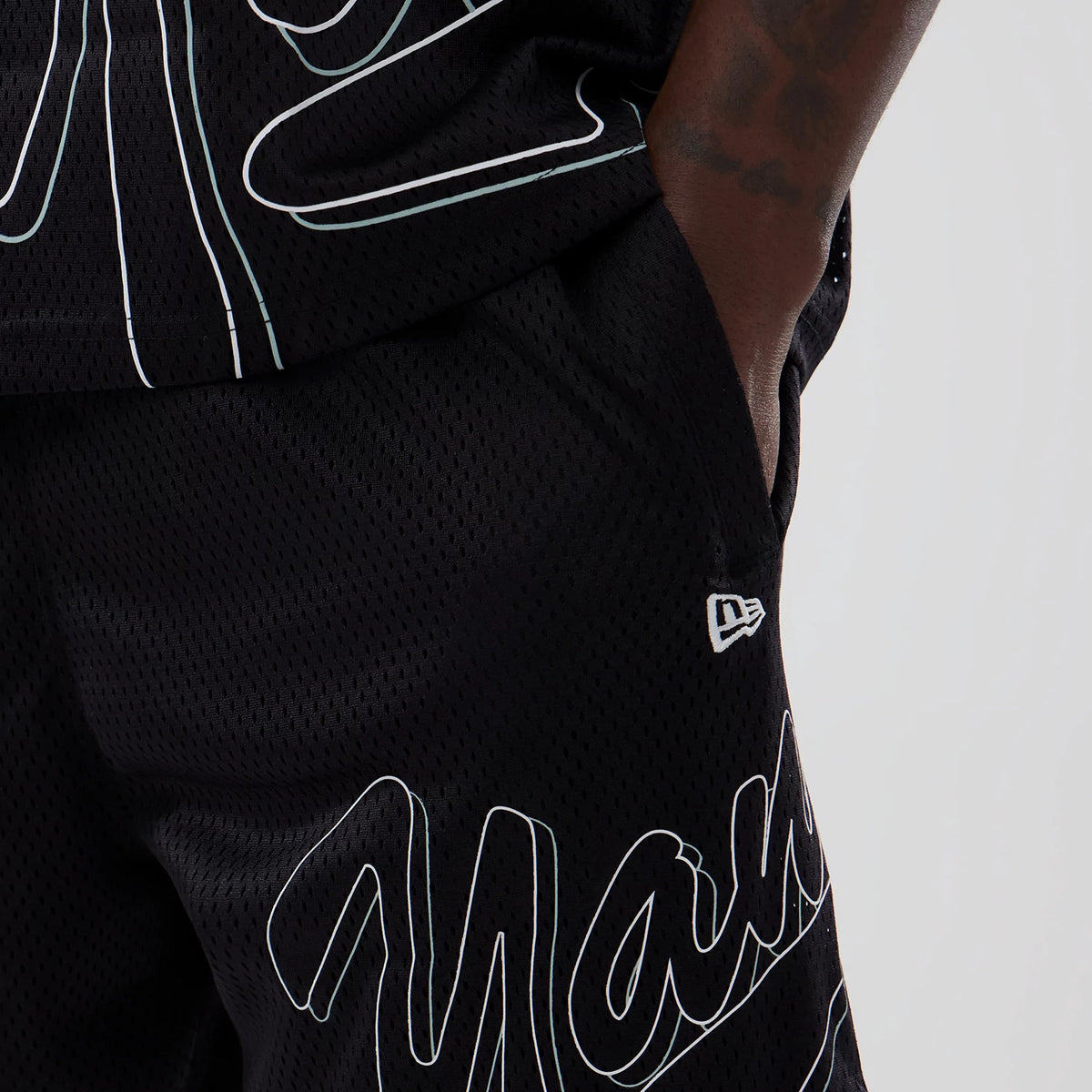 New York Yankees MLB Mix League Black Oversized Mesh Shorts, side view showing black mesh fabric with white outlined graffiti style lettering and a raised New Era logo near the front pocket.