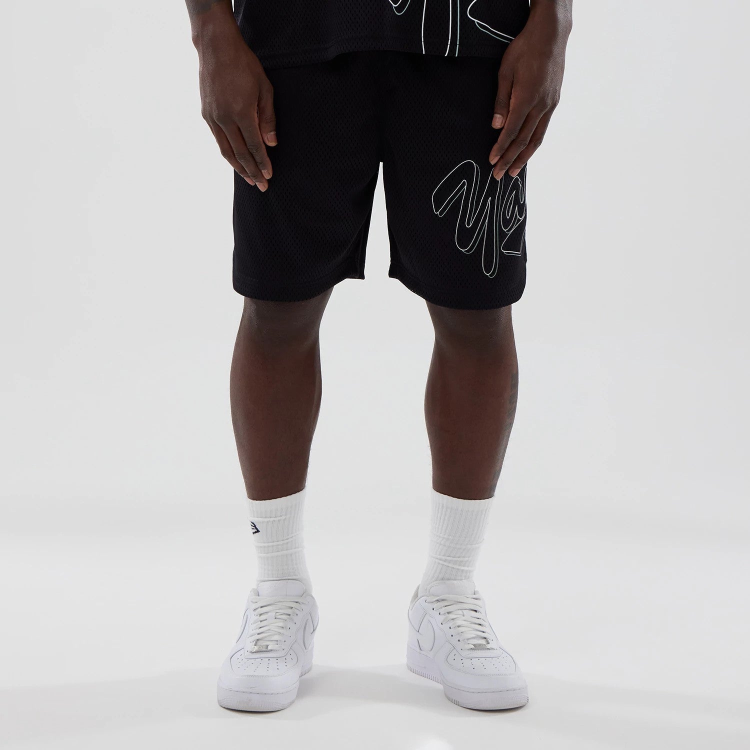 New York Yankees MLB Mix League Black Oversized Mesh Shorts, front view showing the large outlined Yankees script logo on the right leg, the black mesh fabric and the relaxed fit down to the knees.