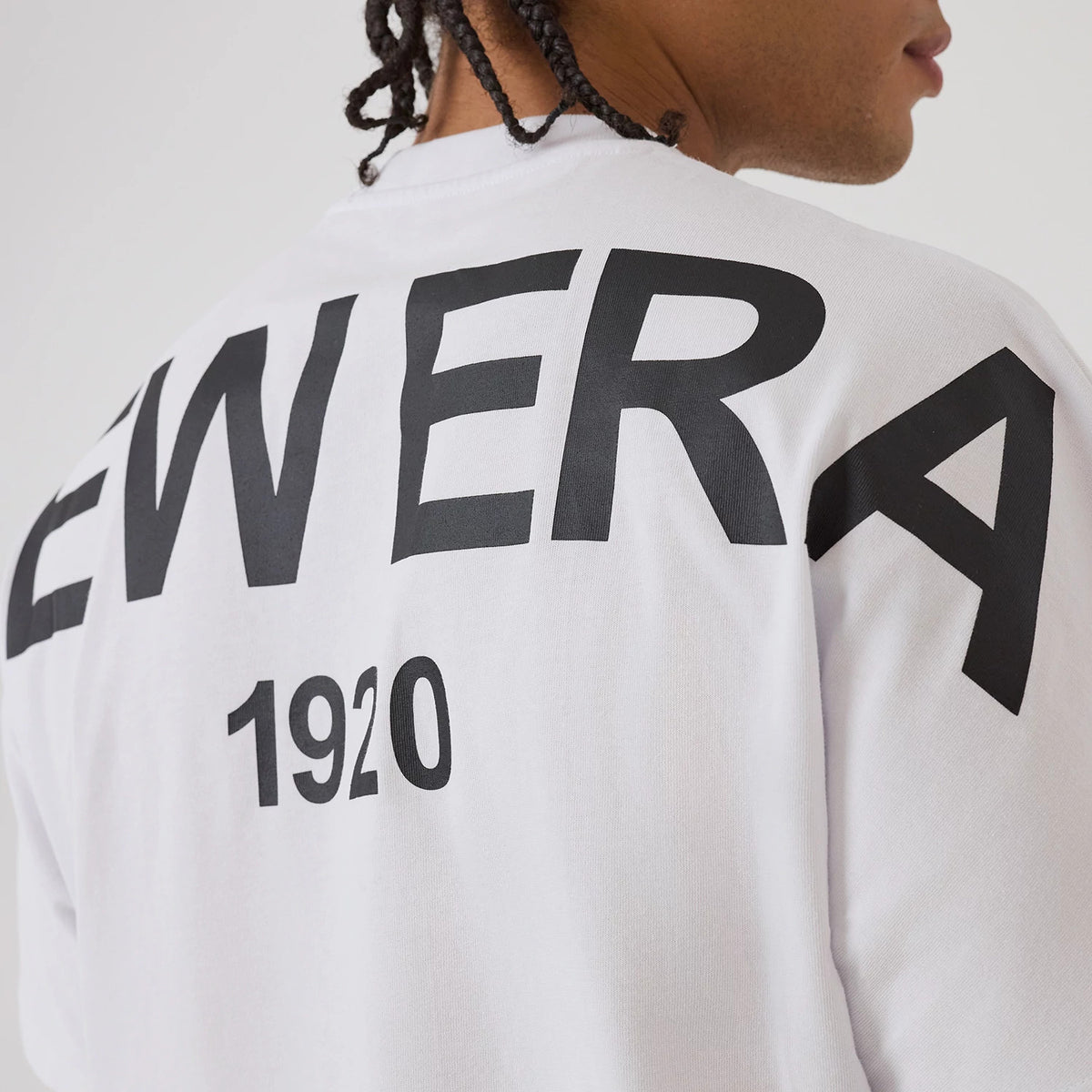 New Era Distressed White T-Shirt, rear view showing bold black New Era lettering across the upper back with 1920 printed below, worn on-model with the shoulder seam and part of the neck visible.