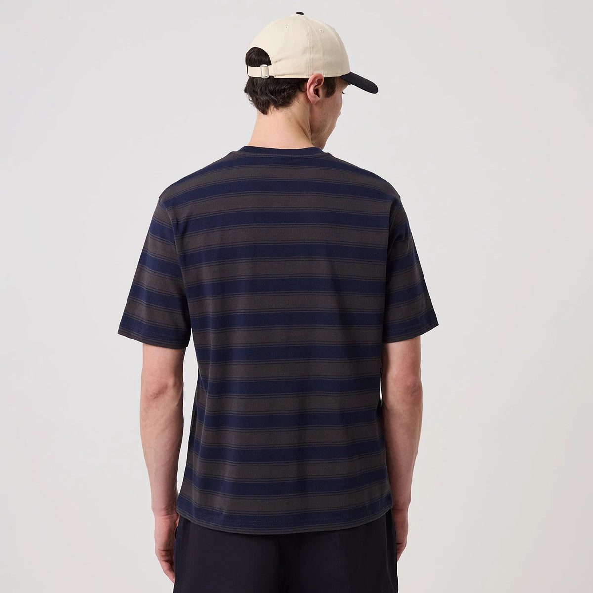 New York Yankees MLB Border Navy Oversized T-Shirt, back view showing horizontal navy and grey stripes and short sleeves, worn by a person in a cream cap featuring a raised New Era logo on the side.