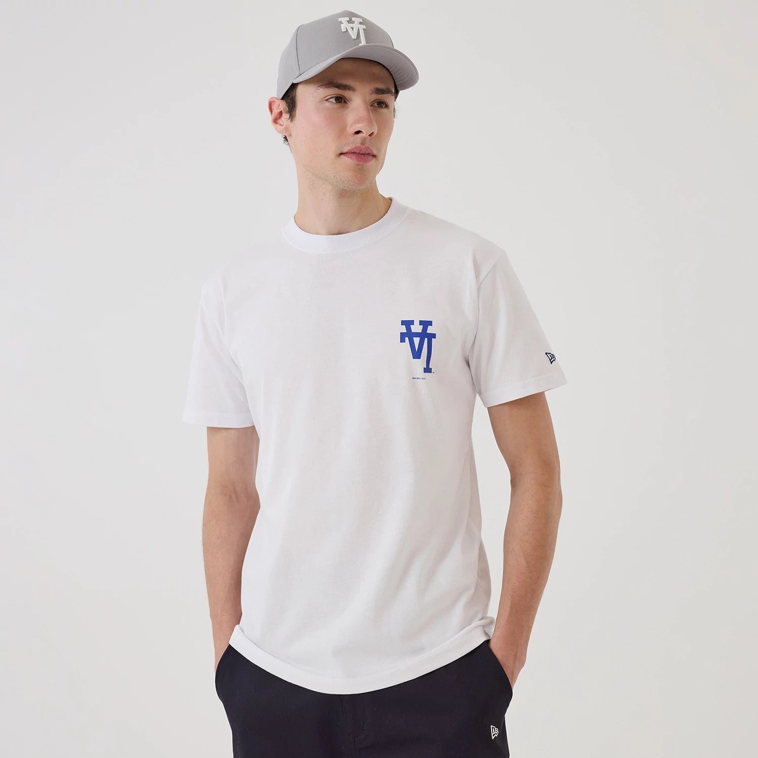 LA Dodgers MLB Upside Down White T-Shirt, on-model view showing a white t-shirt with a blue upside-down LA Dodgers logo on the chest, worn by a person in a grey cap with a white raised New Era logo on the front.