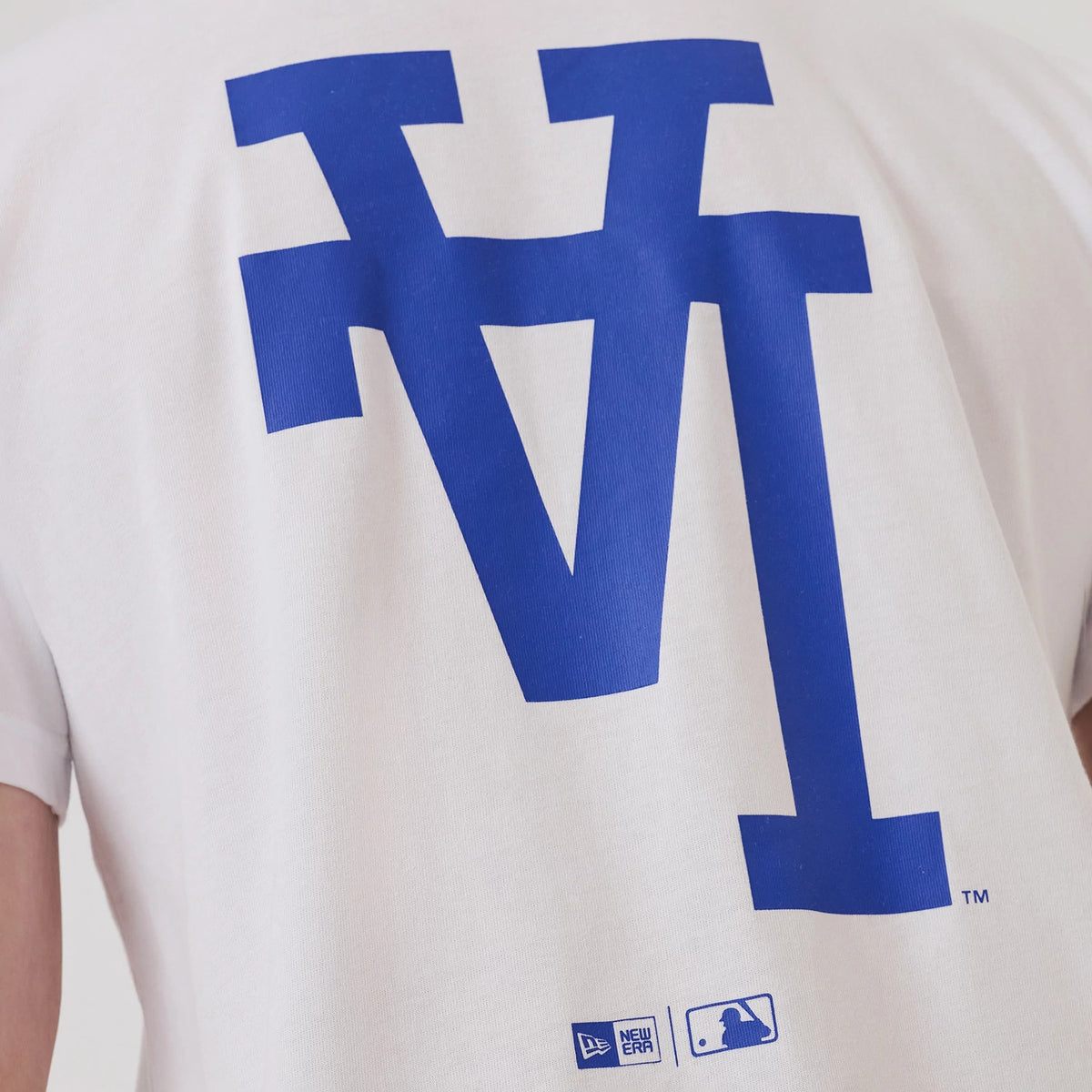 LA Dodgers MLB Upside Down White T-Shirt, rear view featuring large blue upside down LA logo dominating the upper back, debossed New Era and MLB logos near the lower hem on a plain white fabric.