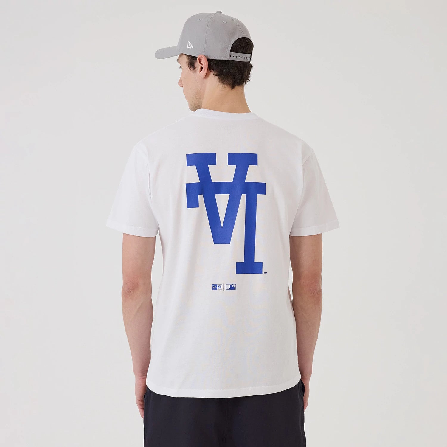 New Era LA Dodgers MLB Upside Down White T-Shirt, rear view showing a blue upside down LA Dodgers logo printed large across the back, worn by a model wearing a grey cap with a debossed New Era logo on the side.