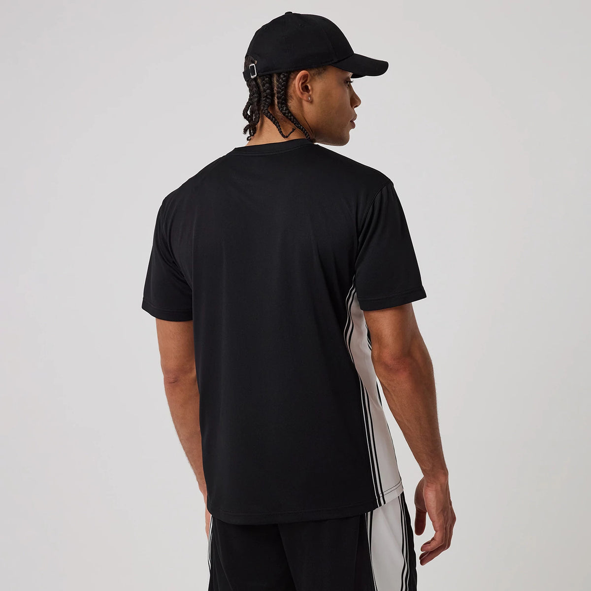 New Era Mesh Black T-Shirt, on-model view showing the back of the black and white t-shirt, with short sleeves and a crew neckline, worn by a person in a black cap with a debossed New Era logo on the cap.
