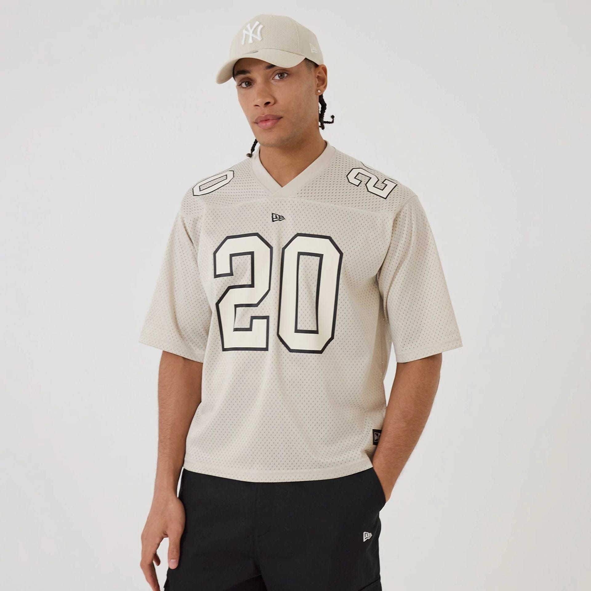The model is wearing this New Era Mesh Football Short Sleeve Shirt in beige. 1