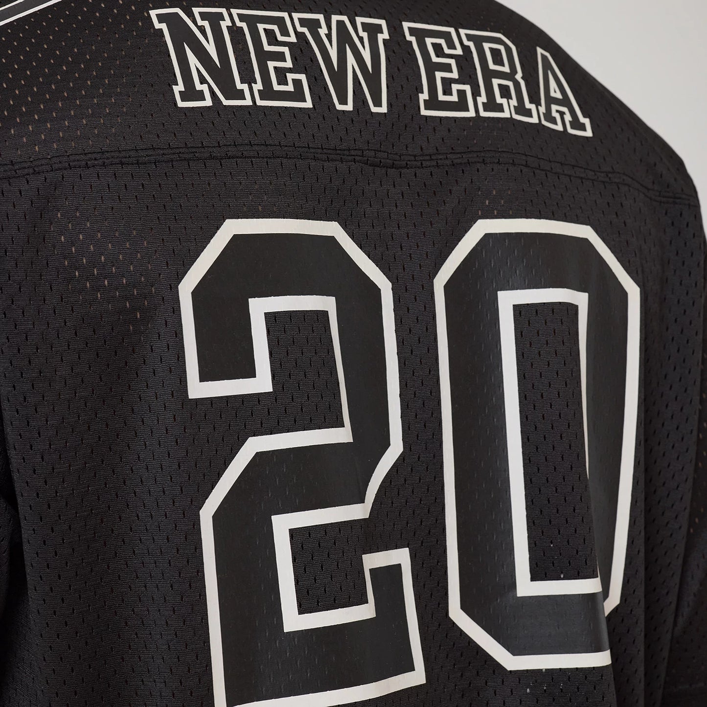 The model is wearing this New Era Mesh Football Short Sleeve Shirt in black. 7