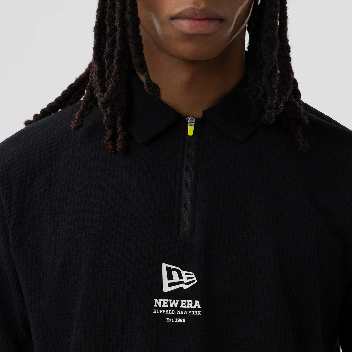 New Era Seersucker Black Polo T-Shirt, front view showing the textured black fabric with a zip at the collar, and a raised white New Era logo centred on the chest with additional text below.