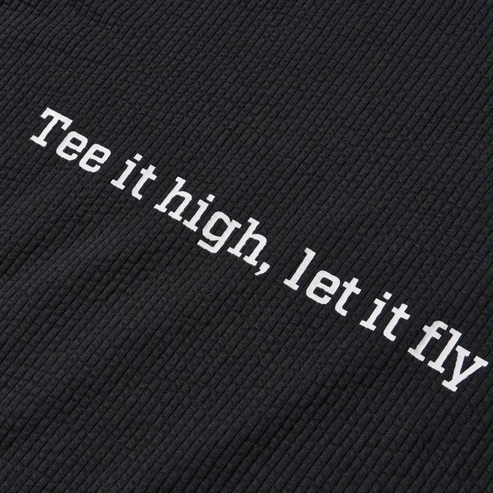 New Era Seersucker Black Polo T-Shirt, close-up view featuring the textured black fabric with the phrase Tee it high, let it fly printed in white letters across the fabric surface.