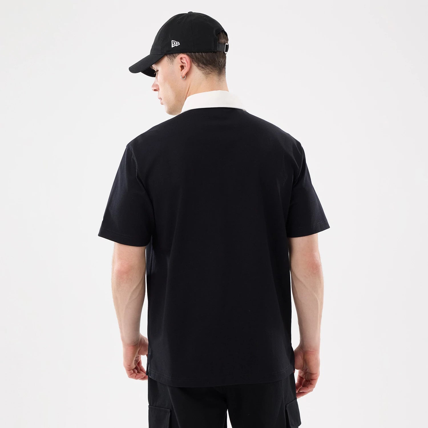 The model is wearing this New Era Short Sleeve Rugby Shirt in black. 2