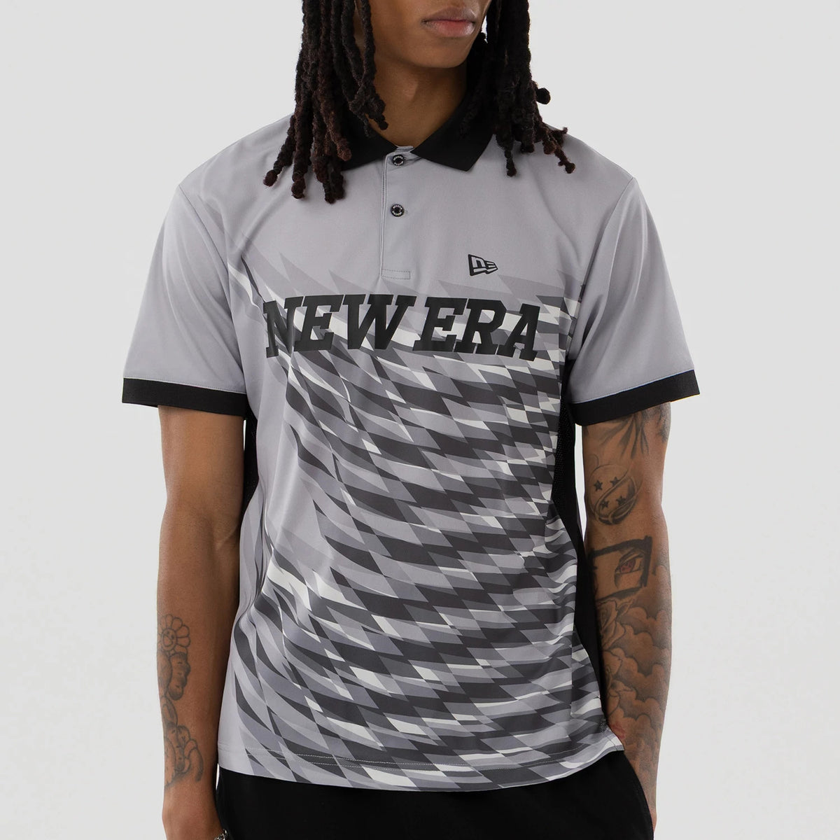 New Era Grid Grey Polo T-Shirt, front view showing a grey polo with a black collar, a bold New Era logo across the chest in black, and a small raised New Era logo on the right side of the chest above a geometric grid pattern.