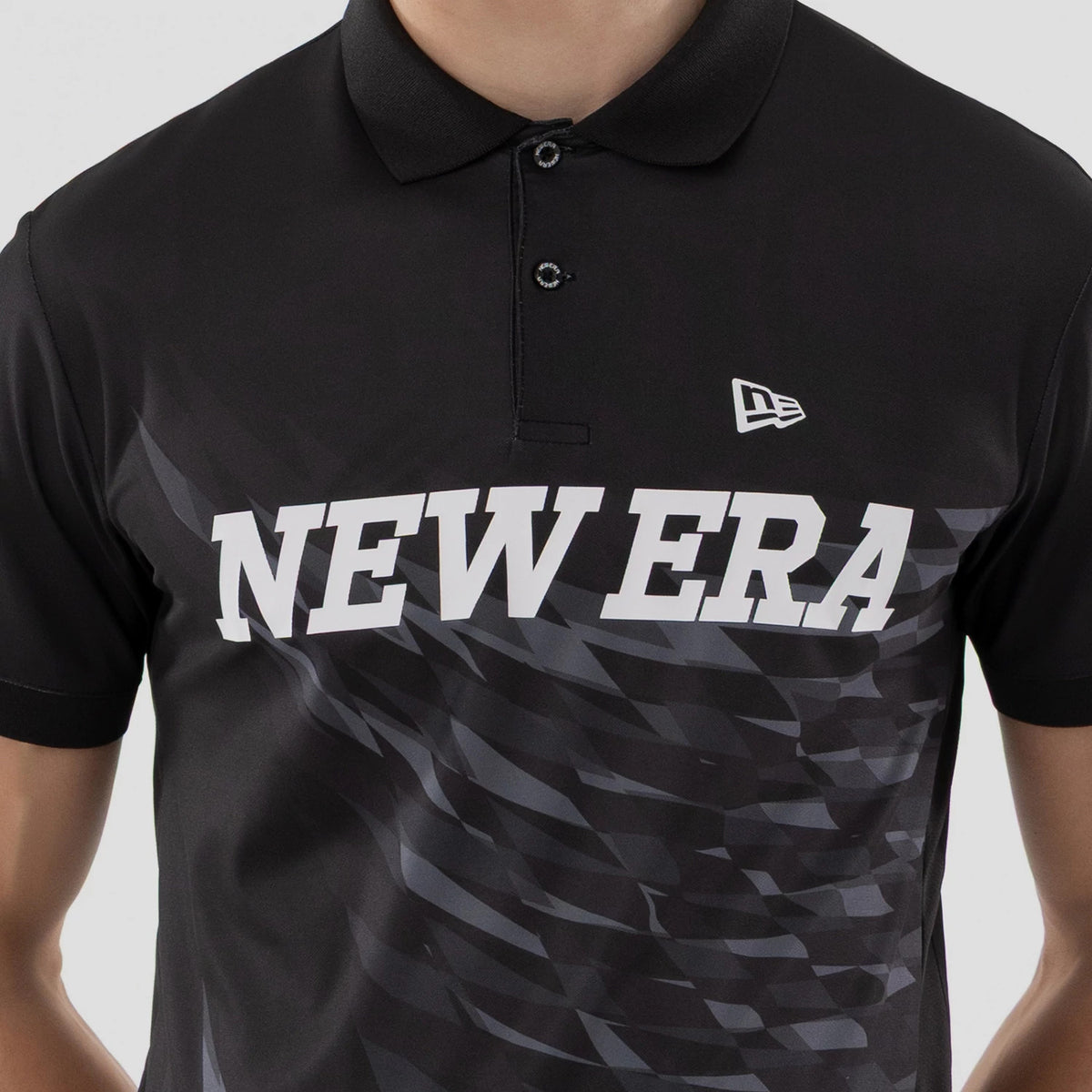 New Era Grid Black Polo T-Shirt, front view showing a white printed New Era logo on the right chest and large white text diagonally across the patterned black fabric, with a pointed collar and black buttons.