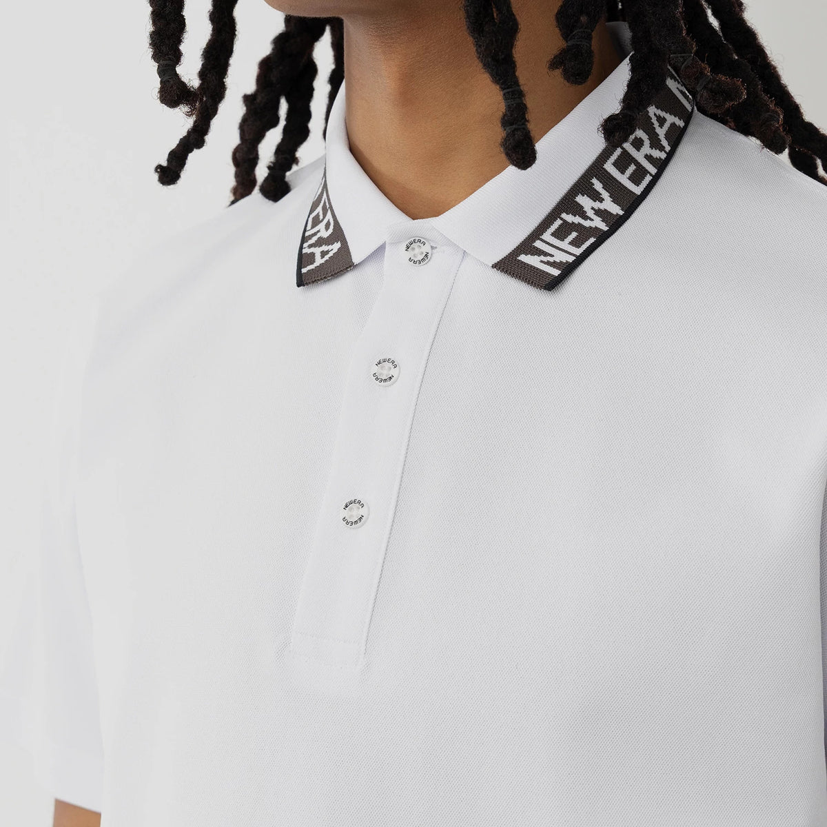 New Era Kanoko White Polo T-Shirt, front view highlighting the black collar with white New Era branding, a series of white buttons running down the placket, and short sleeves on the crisp white fabric.