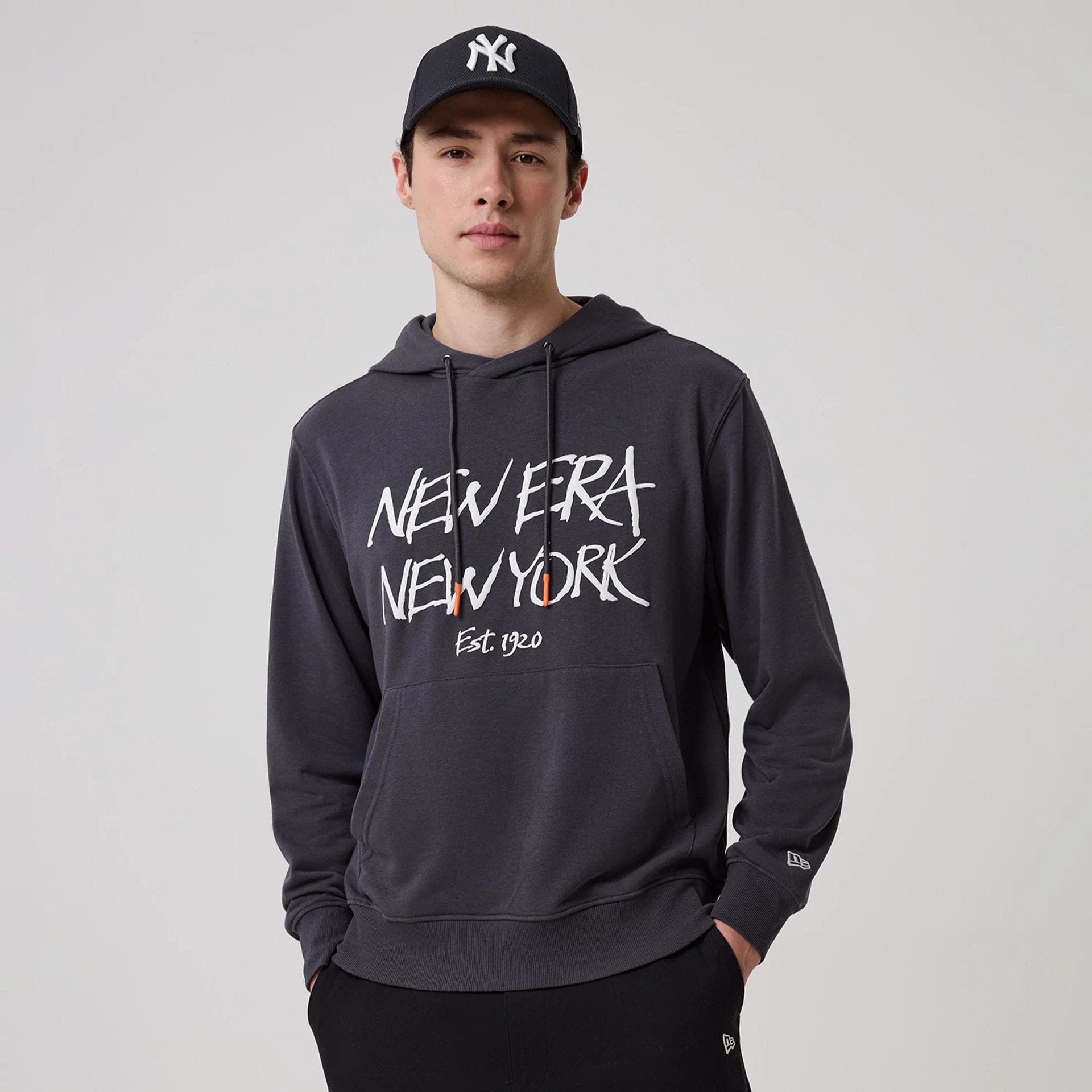 The model is wearing this New Era New York Oversized Pullover Hoodie in dark grey. 1