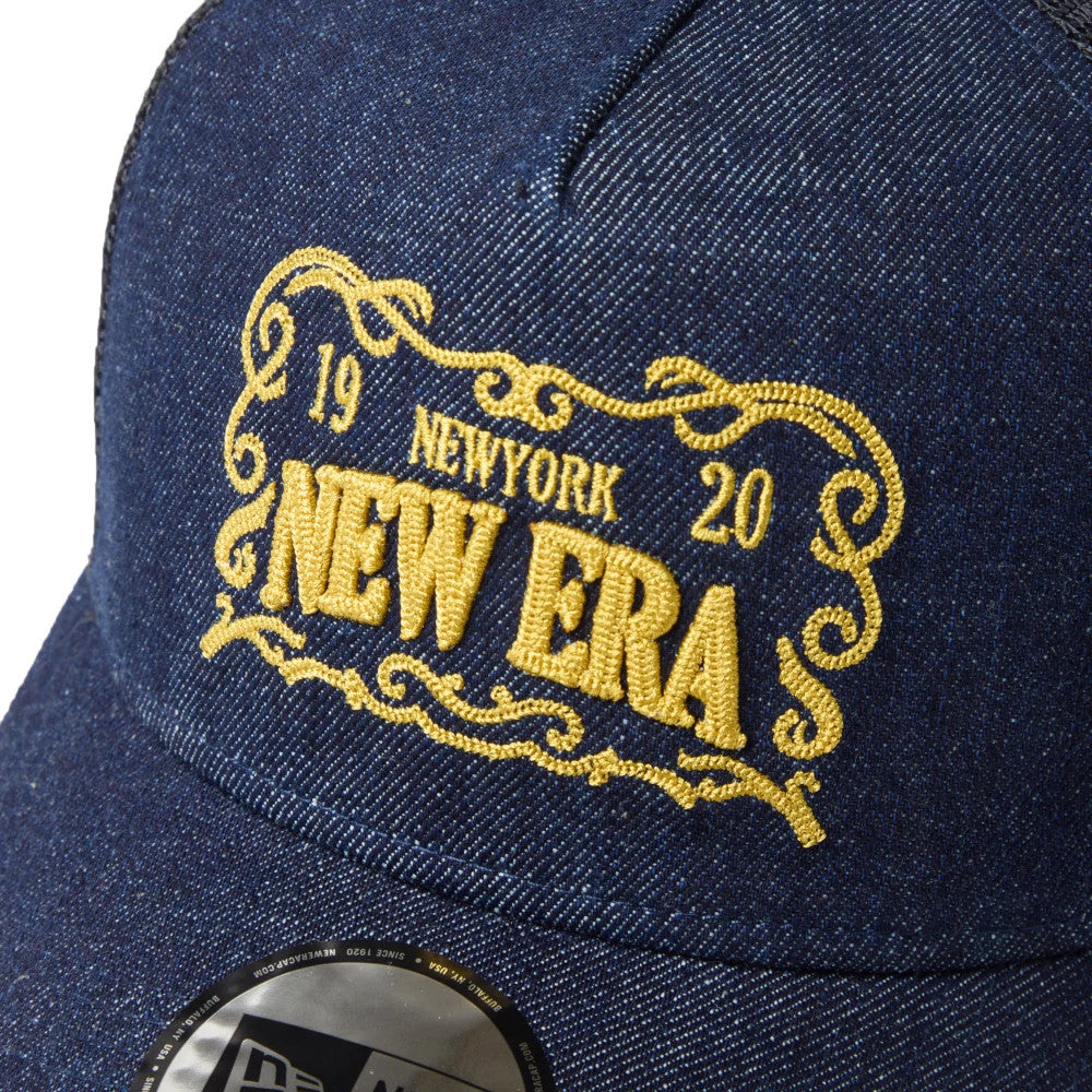 New Era Frame Logo Navy New Era 9FORTY A-Frame Trucker Adjustable Cap, three-quarter view showing raised gold embroidery on the front panel featuring "New Era" text and detailed scrollwork, with a 9FORTY size sticker on the curved visor.