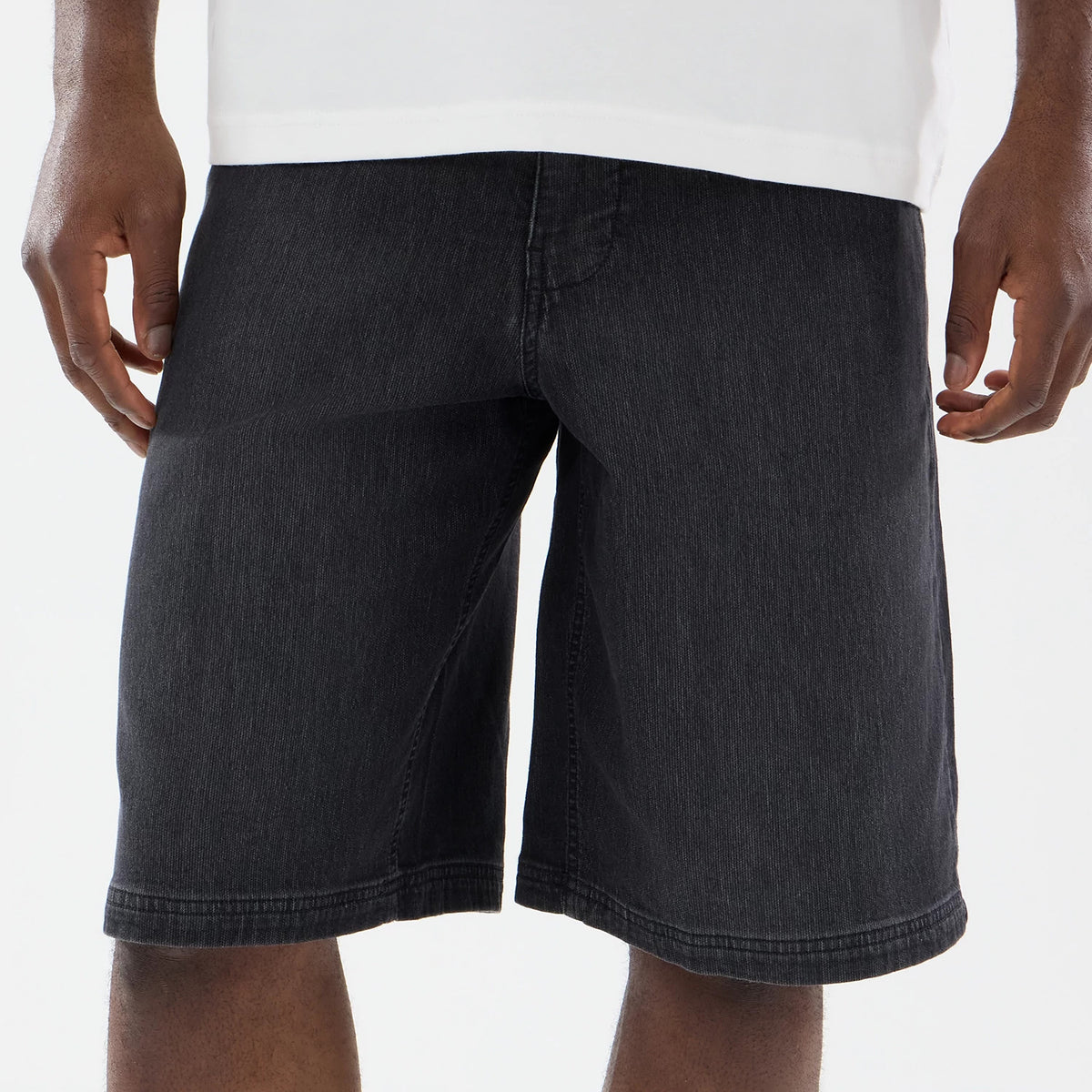 New Era Washed Black Bermuda Shorts, front view showing the washed black fabric with a straight hem falling just above the knee, central front seam detail, worn by a model with hands resting at the sides.