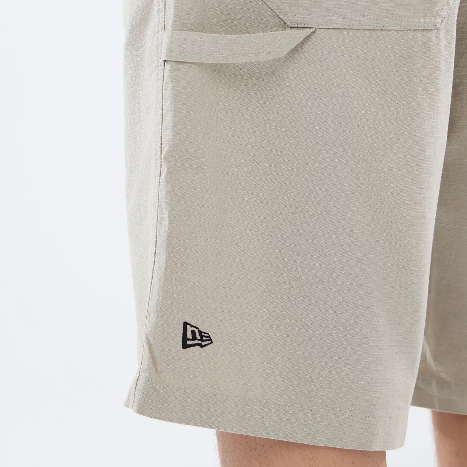The model is wearing this New Era Canvas Bermuda Shorts in beige. 3