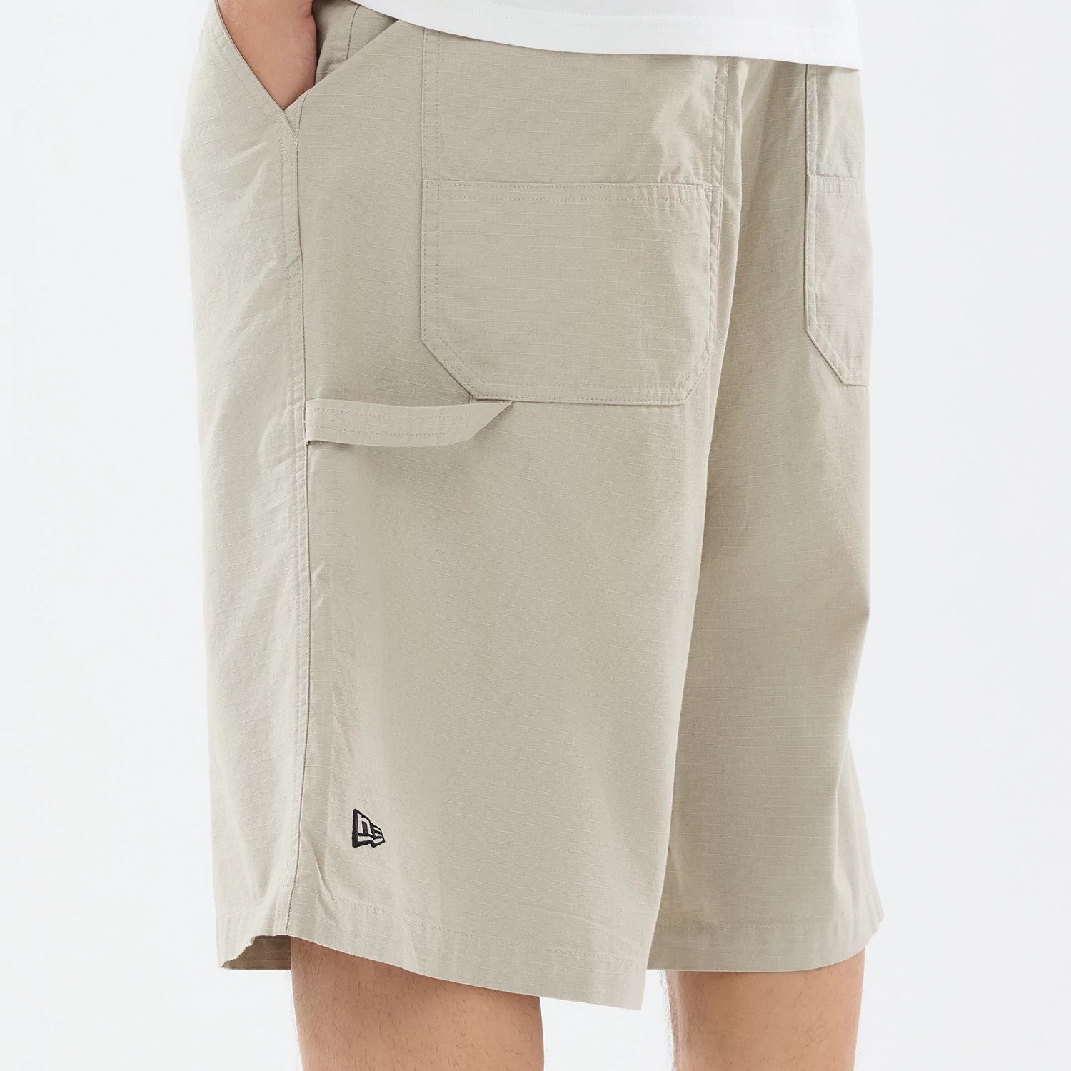 The model is wearing this New Era Canvas Bermuda Shorts in beige. 4