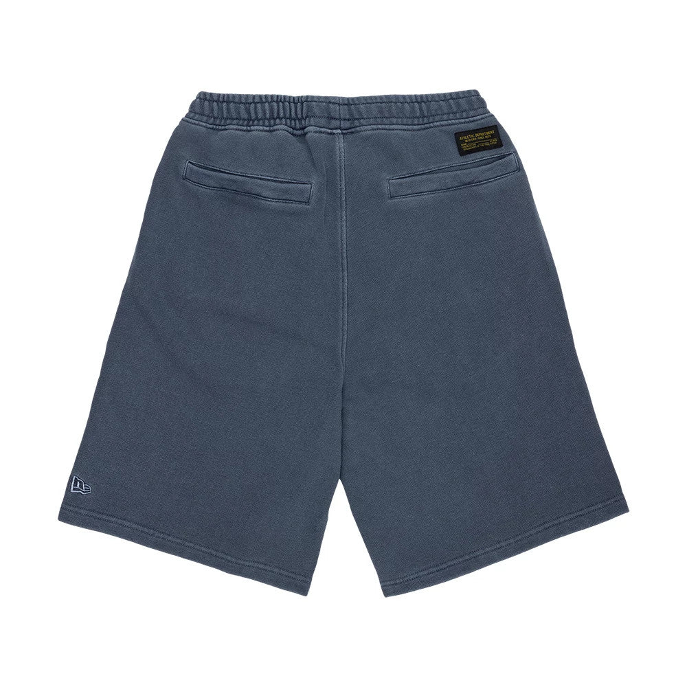 New Era Originators Navy Oversized Shorts, rear view showing the dark blue fabric with elasticated waistband, two horizontal pockets on the back, a debossed New Era logo on the lower left hem, and a black and gold patch near the waistband.