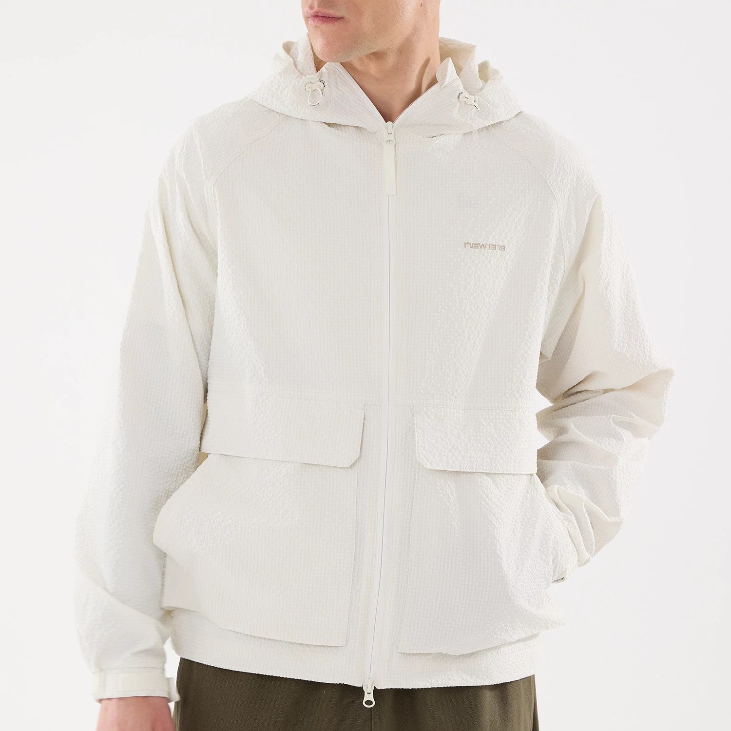 New Era Black Label Open White Jacket, front view showing a textured white jacket with a zipper running centrally, two large flap pockets near the hem, a hood with drawstrings, and a debossed New Era logo on the chest.