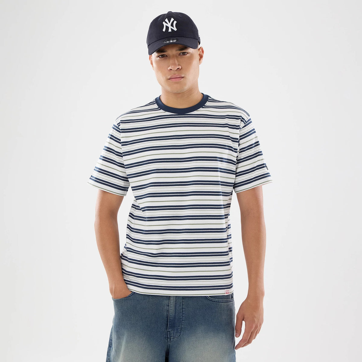 New Era Boarder Stripe White T-Shirt, on-model view showing a navy and white striped T-shirt with a navy ribbed collar, paired with a navy cap featuring a white embossed logo on the front.