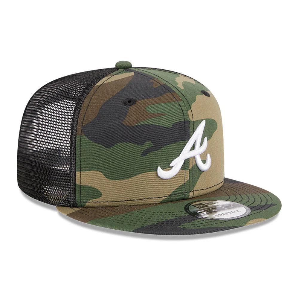 Atlanta Braves MLB Evergreen Camo New Era 9FIFTY Trucker Adjustable Cap, three-quarter view with a white embroidered A logo on the front panel and a black mesh back, featuring a 9FIFTY size sticker on the flat camouflage visor.
