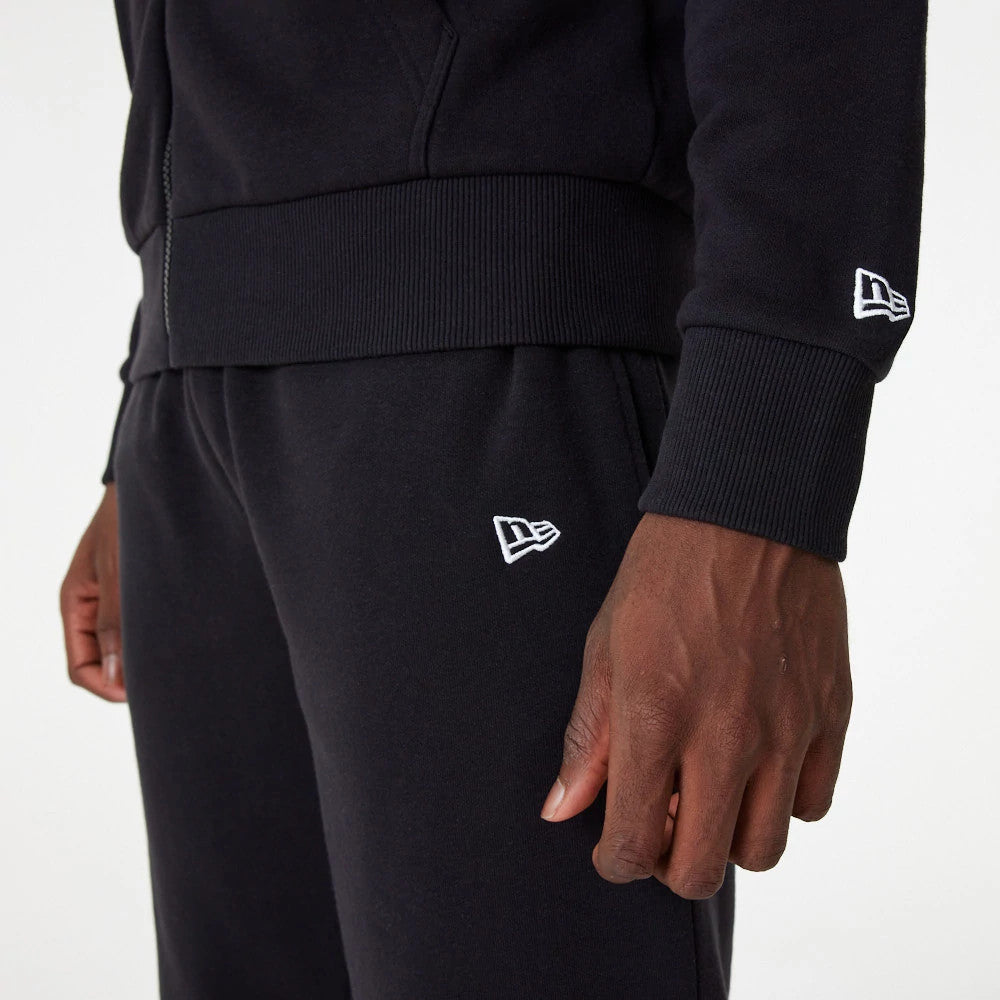 LA Dodgers MLB Essential Black Full Zip Hoodie, side view showing a black hoodie sleeve with a raised white New Era logo near the cuff, paired with matching black trousers featuring a matching logo on the hip.