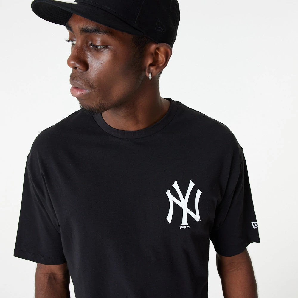 New Era New York Yankees MLB Essential Black Oversized T-Shirt, on-model view showing a man in a black T-shirt with a white printed NY Yankees logo on the chest and a small New Era logo on the left sleeve.