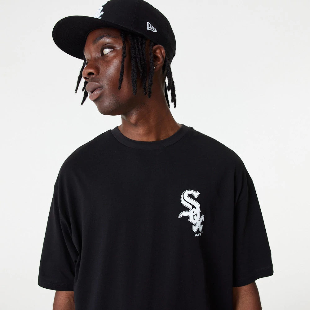 Chicago White Sox MLB Essential Black Oversized T-Shirt, on-model view showing the black T-shirt with a white embroidered Chicago White Sox logo on the chest, paired with a matching black cap featuring a white embroidered New Era logo on the side.