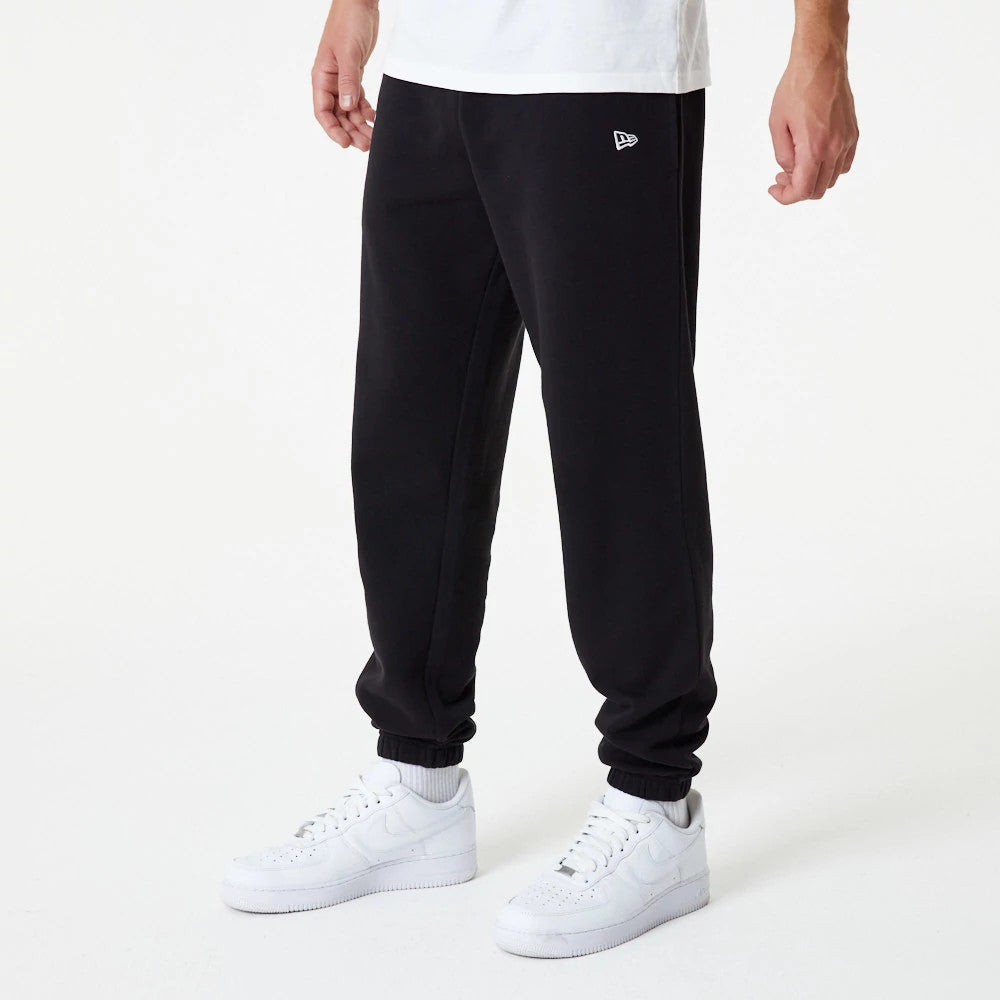 New York Yankees MLB Essential Black Joggers, on-model view showing the New Era flag logo embroidered on the left hip, paired with white trainers and a white t-shirt for a casual look.