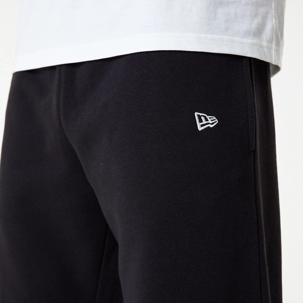 New York Yankees MLB Essential Black Joggers, close-up on a model showing the white New Era flag logo embroidered near the left pocket, paired with a white T-shirt for a casual look.