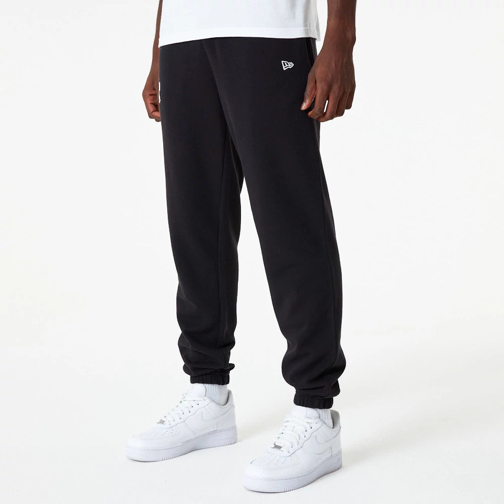 LA Dodgers MLB Essential Black Joggers, front view on a model styled with a white T-shirt and white trainers, featuring an embroidered New Era flag logo on the upper left leg near the pocket.