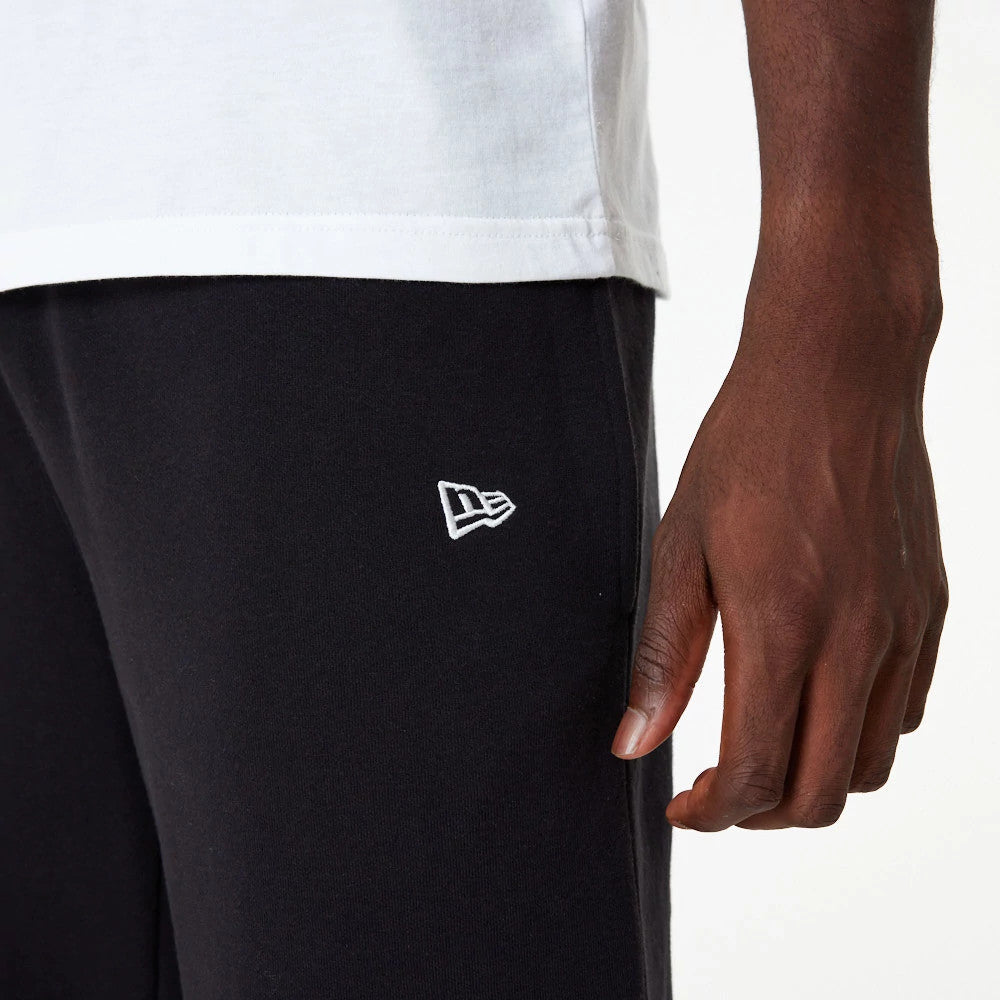 LA Dodgers MLB Essential Black Joggers, on a model showing the white New Era flag logo embroidered on the left thigh near the side seam, paired with a white T-shirt and highlighting the joggers' slim fit.