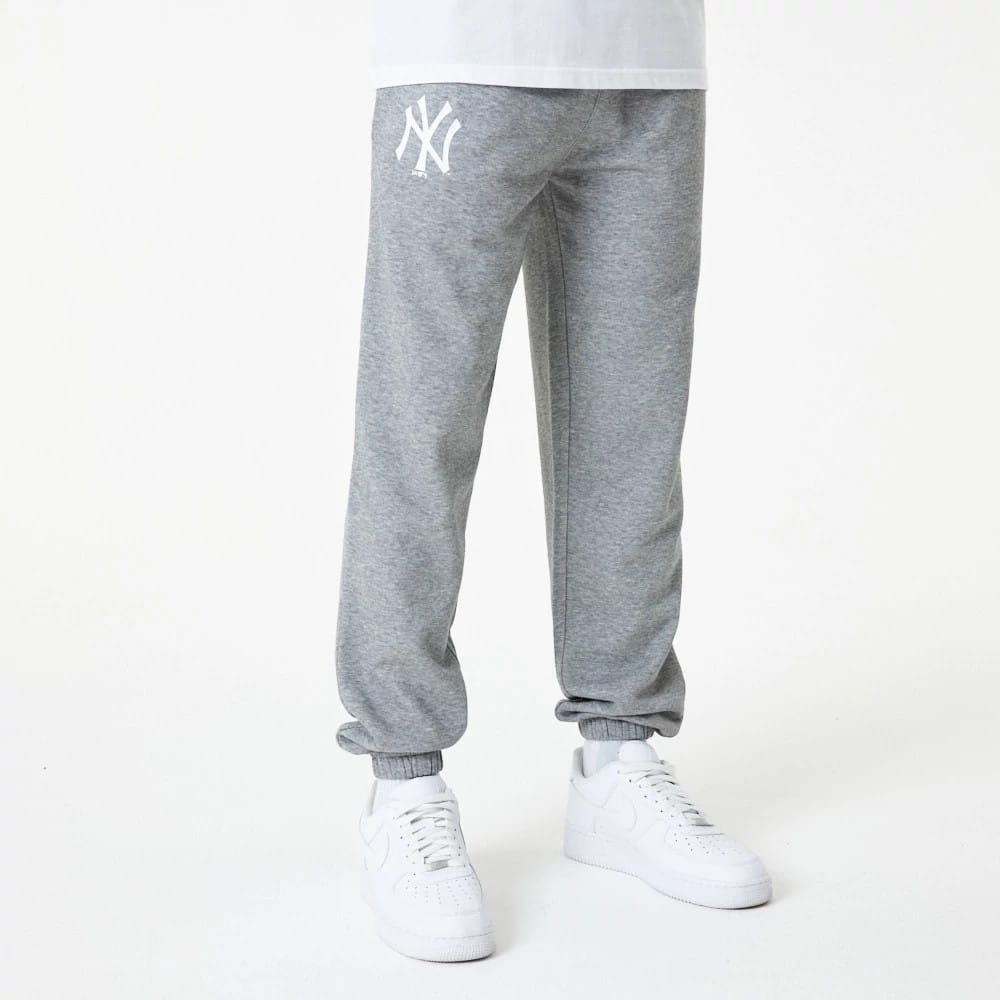 New York Yankees MLB Essential Grey Joggers, front view on a model wearing white trainers, showing the white NY logo embroidered on the upper left leg, with elasticated cuffs and a relaxed fit.