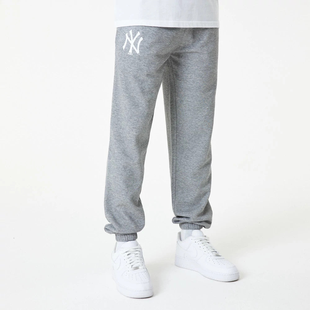 New York Yankees MLB Essential Grey Joggers, front view on a model wearing white trainers, showing the white NY logo embroidered on the upper left leg, with elasticated cuffs and a relaxed fit.