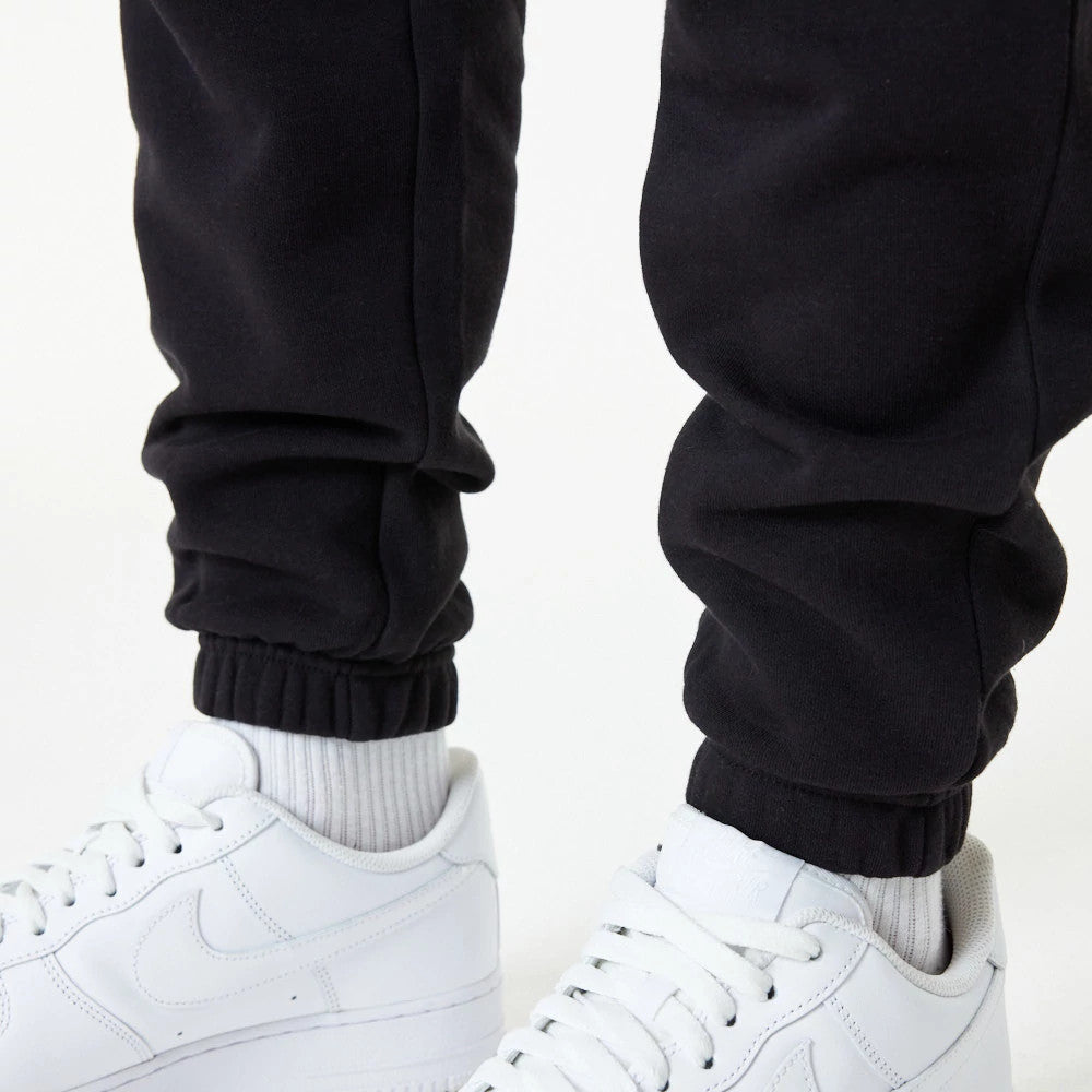 Chicago Bulls NBA Essential Black Joggers, close-up on a model wearing white sneakers, highlighting the elasticated cuffs and smooth black fabric for a casual and comfortable appearance.