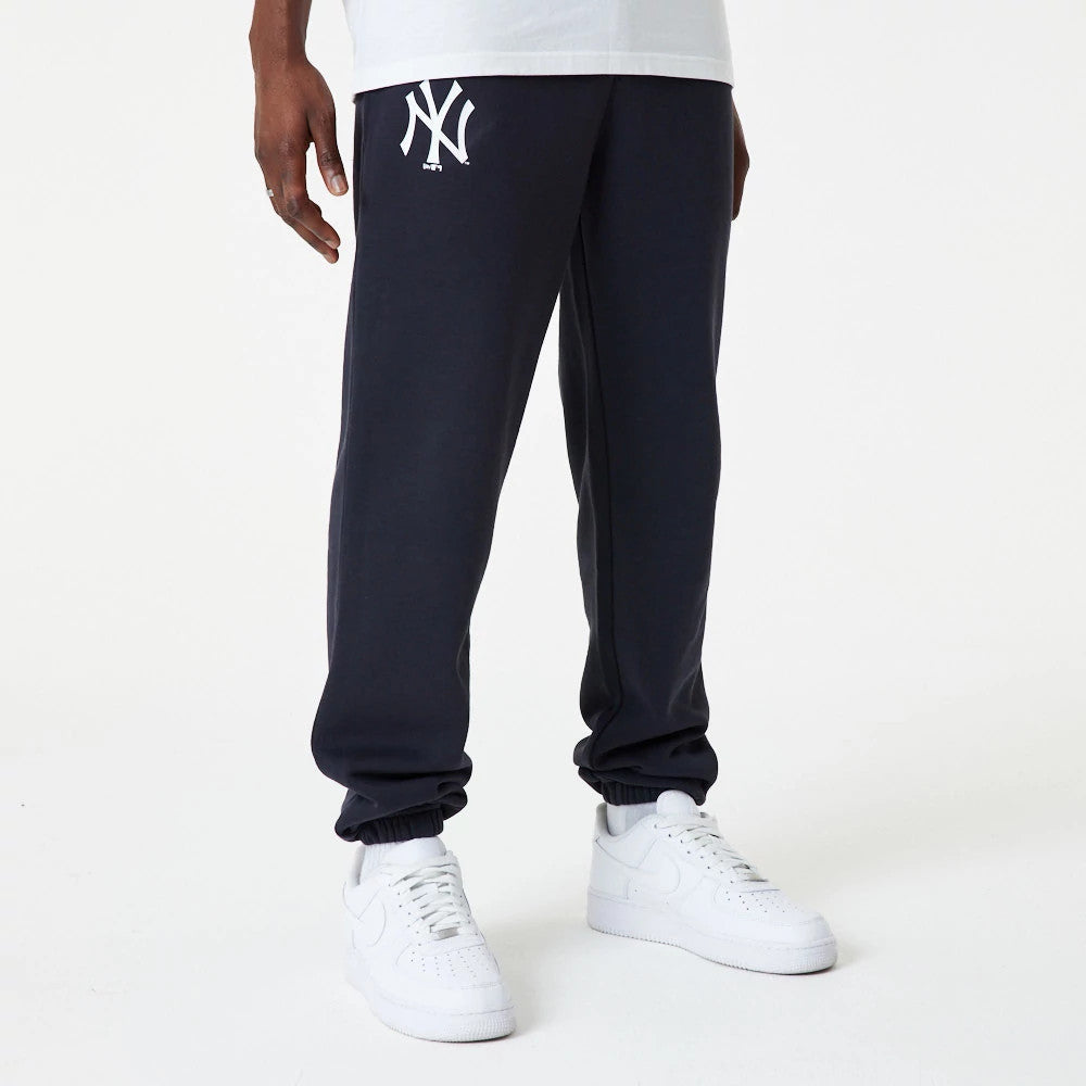 New York Yankees MLB Essential Navy Joggers, front view on a model wearing white trainers, featuring the white embroidered Yankees logo on the left upper thigh and elasticated cuffs.