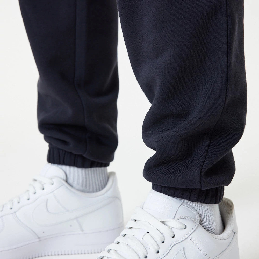 New York Yankees MLB Essential Navy Joggers, front view on a model showing elasticated cuffs resting above white trainers, highlighting the comfortable fit and casual style of the navy joggers.
