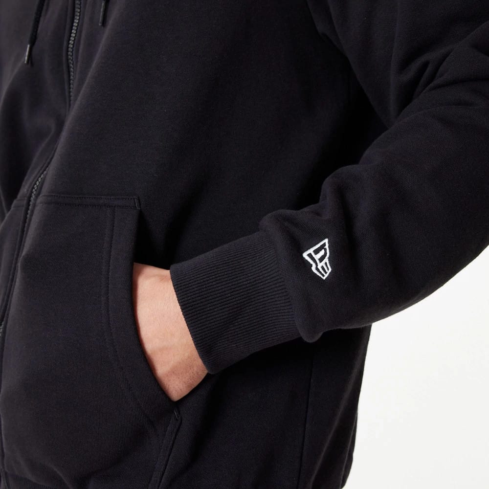 Chicago Bulls NBA Essential Black Full Zip Hoodie, side view showing a black sleeve with a ribbed cuff and a white embroidered logo on the wrist, alongside a partially zipped front and a visible front pocket with a hand inside.