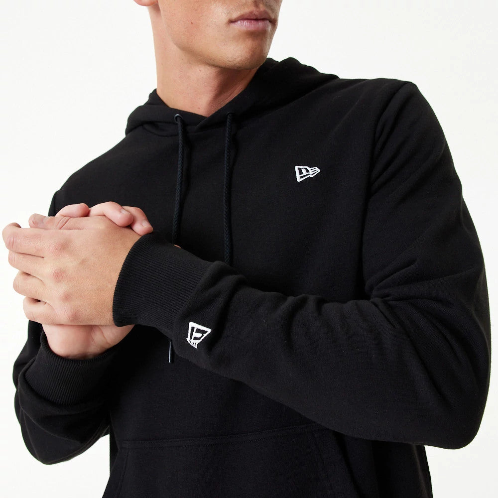 New Era Essential Black Pullover Hoodie, front view showing the black fabric with a white raised New Era logo on the chest, a drawstring hood, ribbed cuffs, and an additional white raised logo on the cuff.