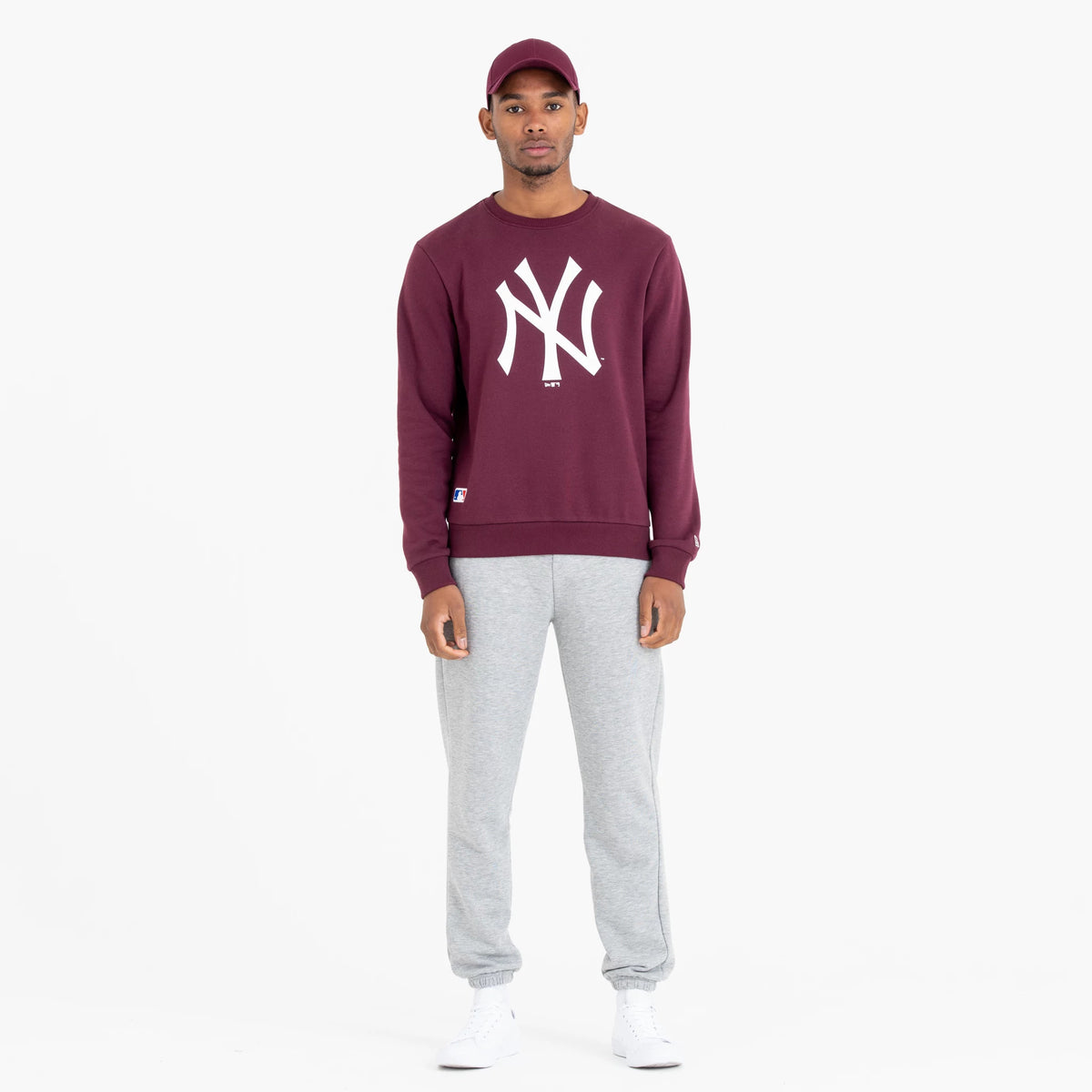 New York Yankees MLB Regular Dark Purple Crew Neck Sweatshirt, front view on a model wearing grey joggers and white sneakers, featuring a large white NY logo on the chest and a small MLB patch above the hem.