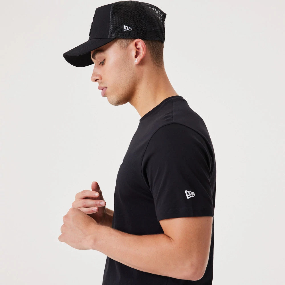 New Era Essential Black T-Shirt, on-model view showing a black short-sleeve design with a white embroidered New Era logo on the sleeve, paired with a black cap featuring a raised logo on the side.